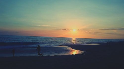 Silhouette man standing on beach against sky during sunset