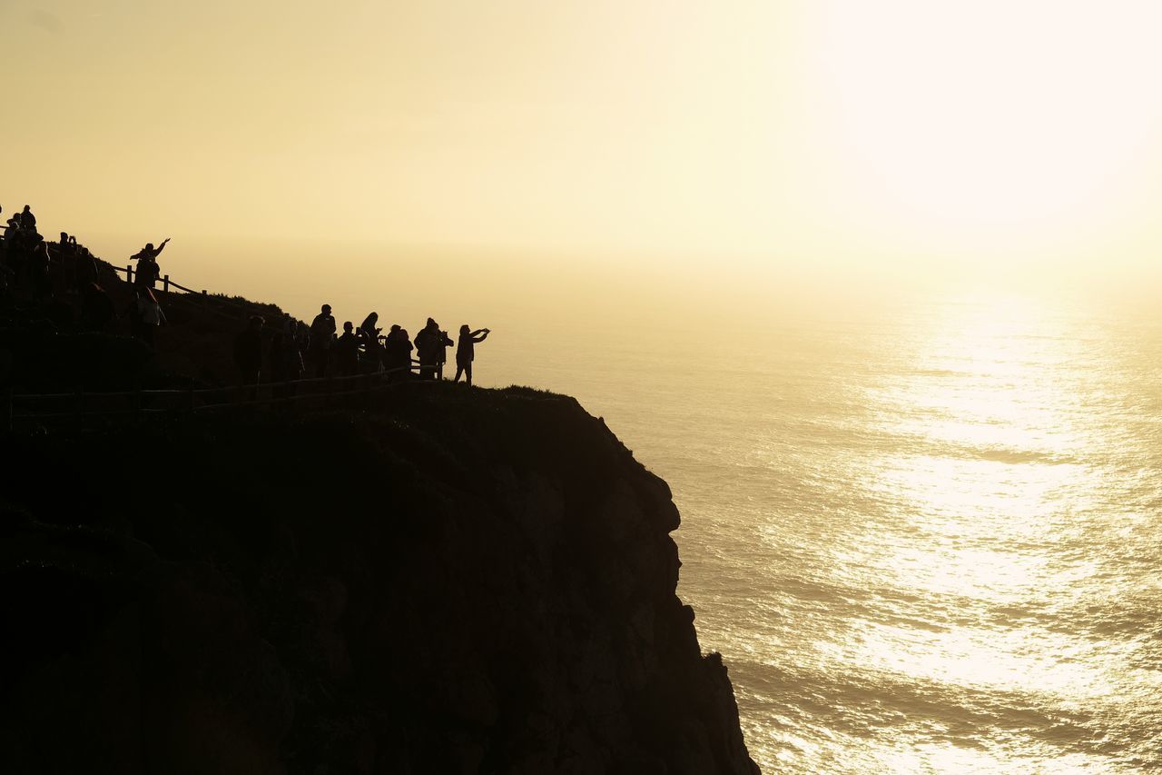 SILHOUETTE OF PEOPLE ON SEA AGAINST SKY