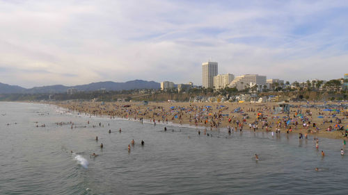 People on beach against sky in city