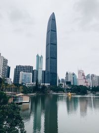 Modern buildings by river against sky in city