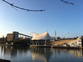 Birds flying over river against clear sky