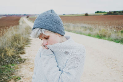 Close-up of woman wearing knit hat while standing on dirt road