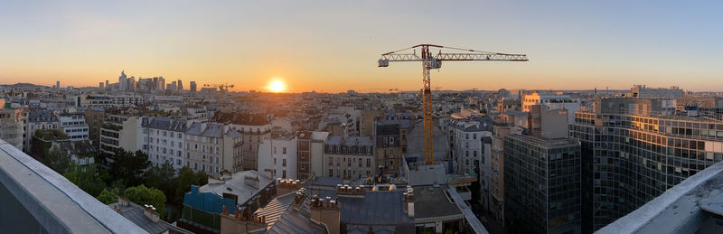 High angle view of construction site by buildings against sky during sunset