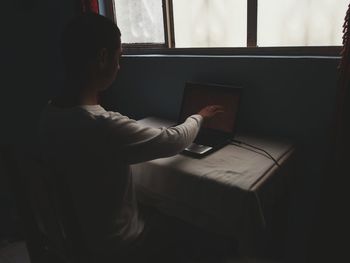 Man touching laptop screen at home