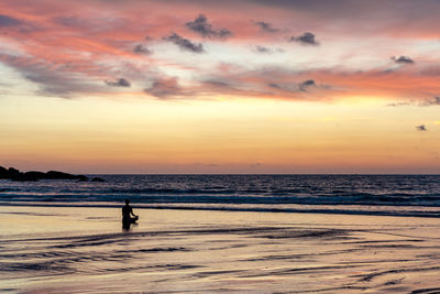 Silhouette man on beach against sky during sunset