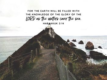 Text on rock by sea against sky