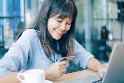 Smiling businesswoman doing online shopping over laptop in office