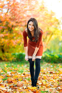 Portrait of smiling young woman standing in park during autumn