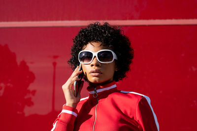 Afro-american woman dressed in sportswear with mobile phone in hand on a red background