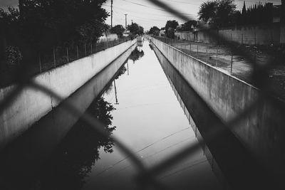 Reflection of woman walking on footbridge against sky