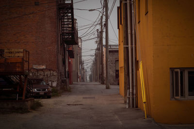 Walkway amidst buildings against sky
