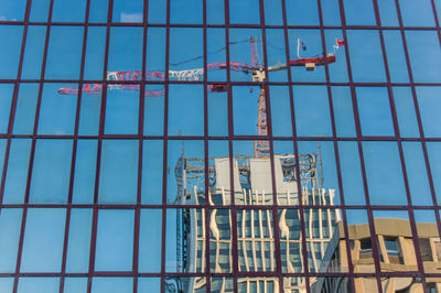 Low angle view of glass building against clear blue sky