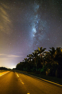 Road amidst trees against sky at night