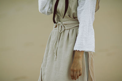 Midsection of woman in traditional clothing standing against brown background