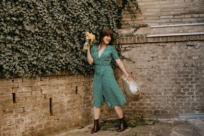 Full length of woman standing against wall