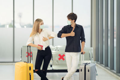 Life during covid-19 pandemic. young man and woman waiting for flying at airport at window 