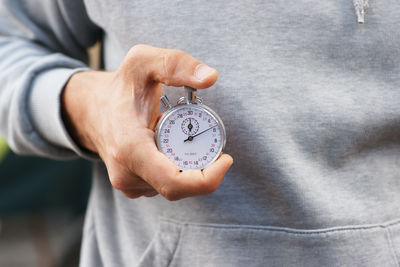 Midsection of man holding stopwatch