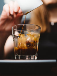 Midsection of woman pouring coffee in glass on table