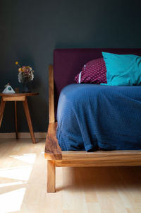 Bed base, bedroom with mat on the floor, clay pot in the background, wooden credenza and mirror.