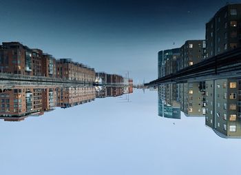 Reflection of buildings in city against clear sky