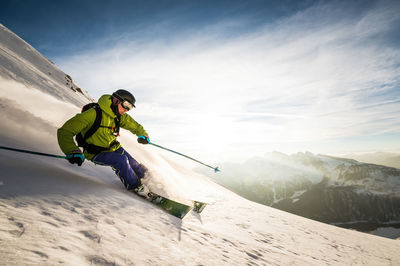 Man skiing on snowcapped mountains against sky