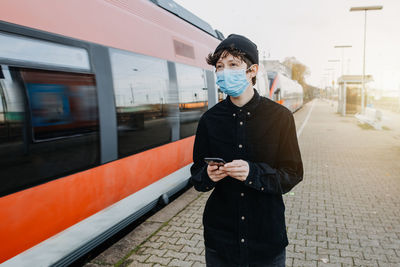 Full length portrait of young man standing on train