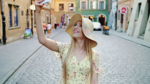 Portrait of young woman standing on street in city