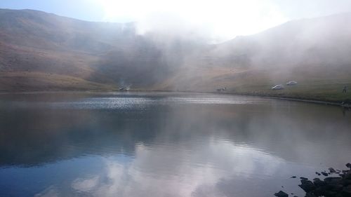 Scenic view of lake by mountains against sky