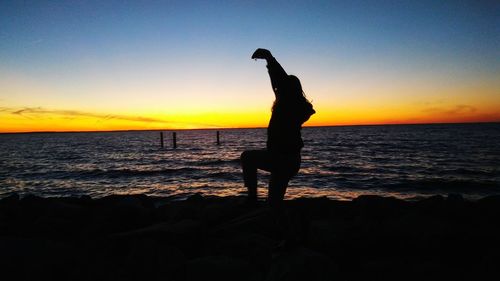 Silhouette woman on beach against clear sky during sunset