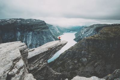 Distant view of man standing on cliff against valley