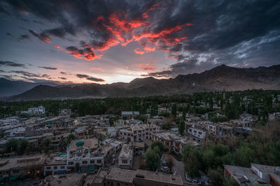 Aerial view of houses and mountains against sky at sunset