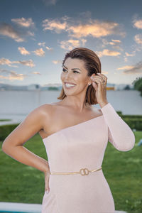 Smiling young woman standing against sky