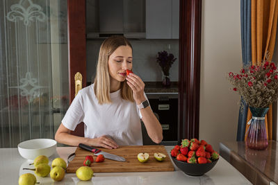 Woman smelling strawberries at home