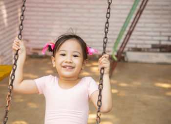 Portrait of a smiling girl on swing in playground