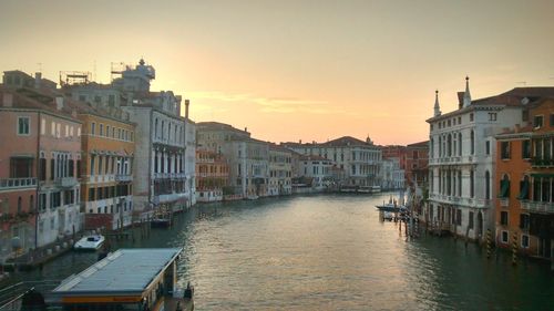 Boats moored in canal amidst buildings against clear sky