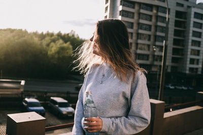 Woman looking away while standing in city