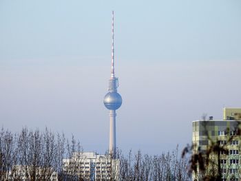Communications tower in city against clear sky
