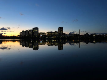 Reflection of illuminated buildings in river against sky