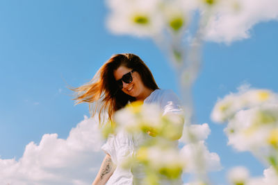 Young woman standing against sky