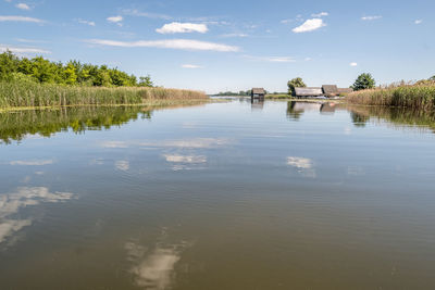 Scenic view of lake with boathouse against sky 