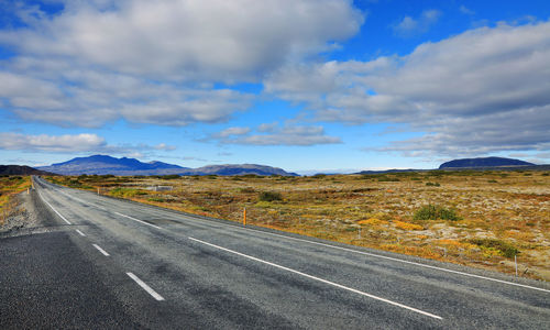 Road leading towards mountains against sky