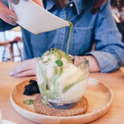 Midsection of woman pouring drink on ice cream at restaurant