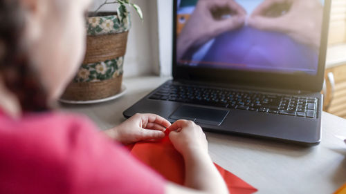 Midsection of girl doing origami at home