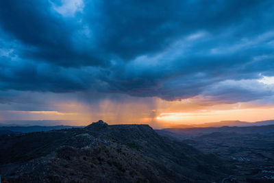 Scenic view of mountain against dramatic sky during sunset