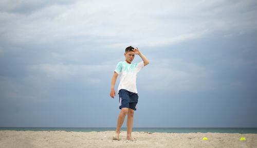 The boy trains on the sand by the sea. general physical preparation. tennis player.