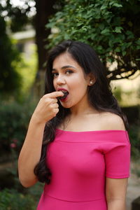 Portrait of beautiful young woman eating while standing outdoors