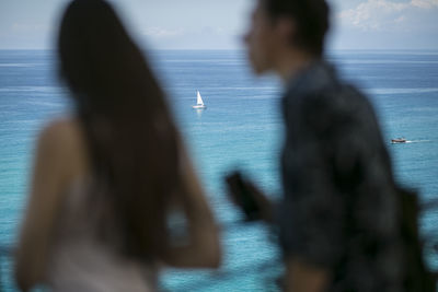 Shadow of people on road by sea