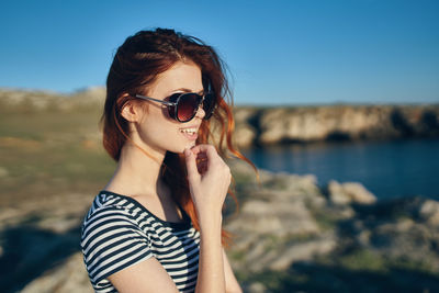 Portrait of woman wearing sunglasses at beach against sky