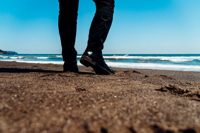 Low section of man standing on sand at beach