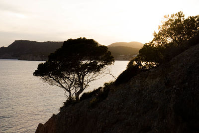 Scenic view of sea by silhouette mountain against sky